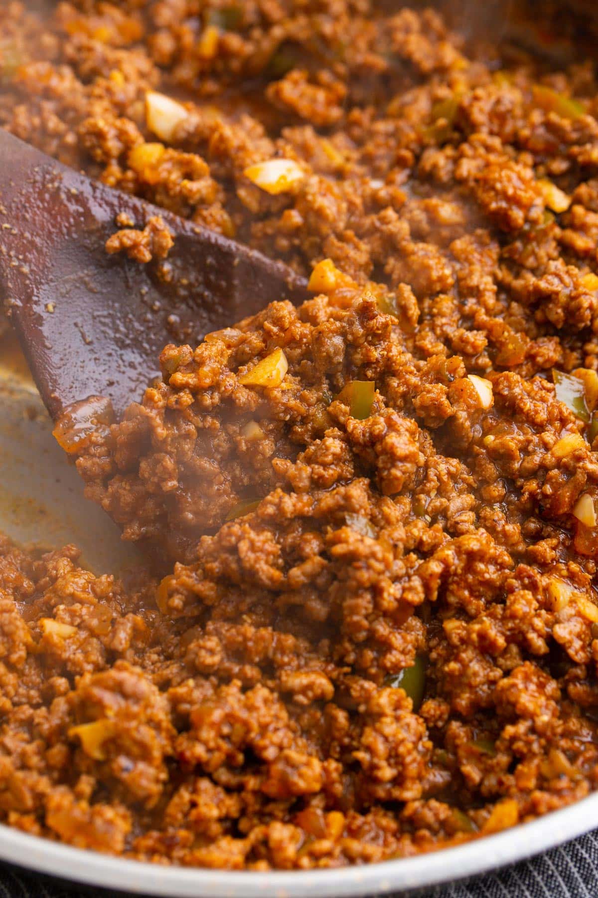 A close up photo of homemade Sloppy Joe sauce simmering in a stainless steel skillet.