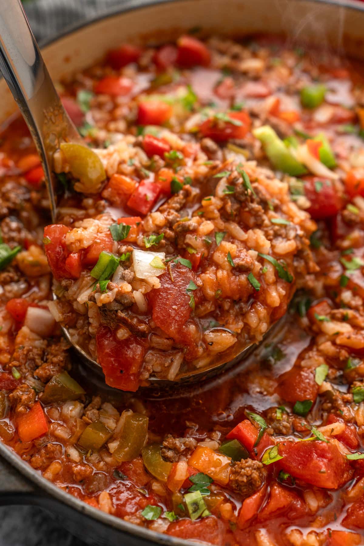 A stainless steel soup ladle filled to the brim with steaming stuffed pepper soup.