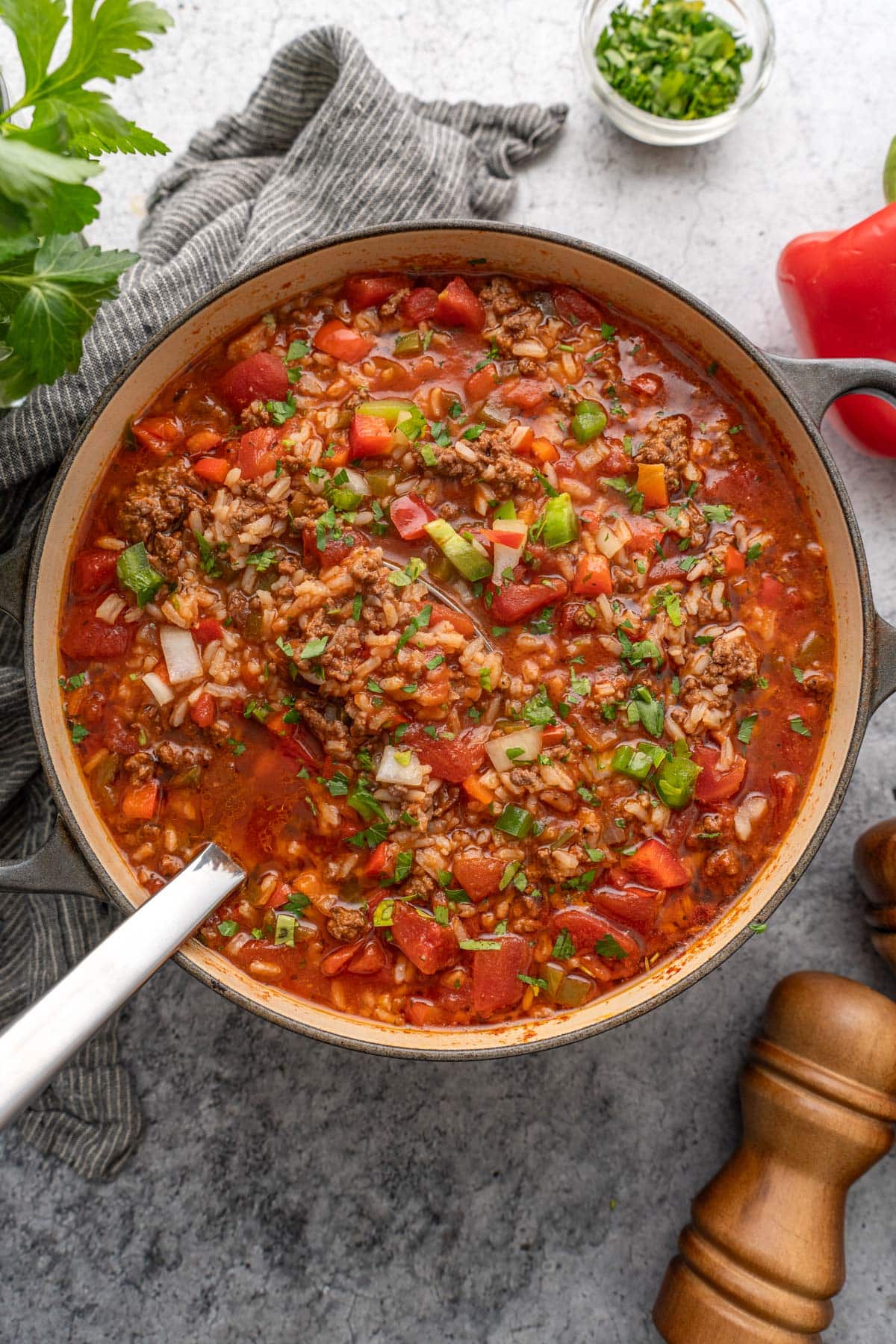 Stuffed pepper soup topped with fresh chopped parsley in a gray cast iron Dutch oven.